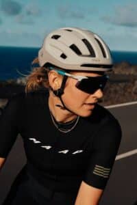 une femme porte un casque de velo a les cheveux au vent